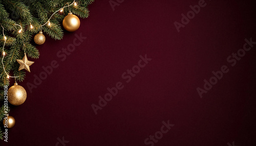 Christmas background with gold ornaments and fir branches on dark red