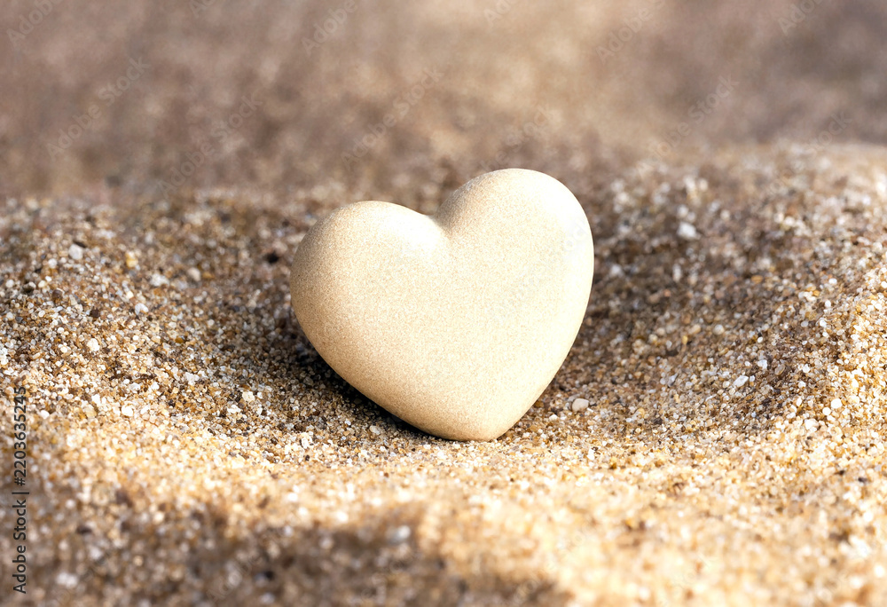 Fototapeta premium Small heartshaped object delicately placed on fine sand background showing simplicity and love concept