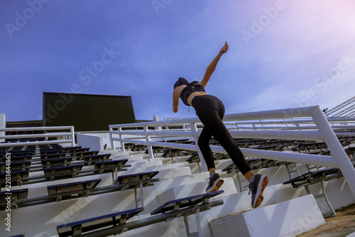 Runners practice stair running to improve their physical strength..Woman runner running sprinting up stairs at stadium.