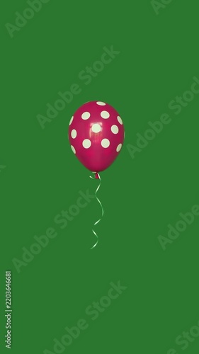 Pink polka dot balloon floating in the air on green screen vertical video.