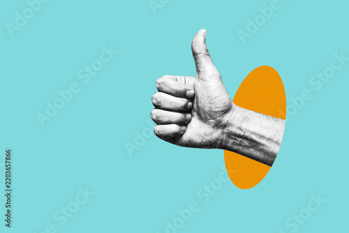 Human hand showing thumbs up gesture on abstract collage background