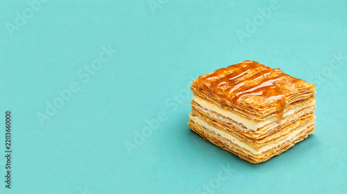 Delicious mille-feuille pastry with caramel drizzle on a vibrant teal background