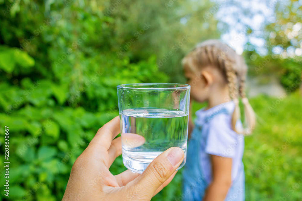Fototapeta premium Little girl taking glass of clean water from adult hands in nature