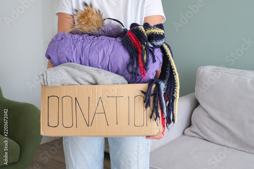 Donation box with winter clothes.  The volunteer is holding a cardboard box with warm garment.