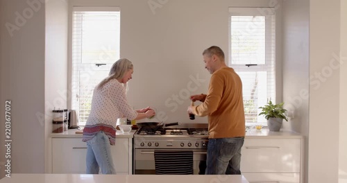 Senior couple cooking together in modern kitchen, enjoying quality time at home