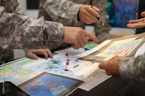 Experienced military hands focused intensely around a tactical map table, actively collaborating and planning precise strategic operations, operational logistics