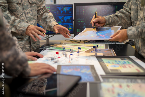 Experienced military hands focused intensely around a tactical map table, actively collaborating and planning precise strategic operations, operational logistics