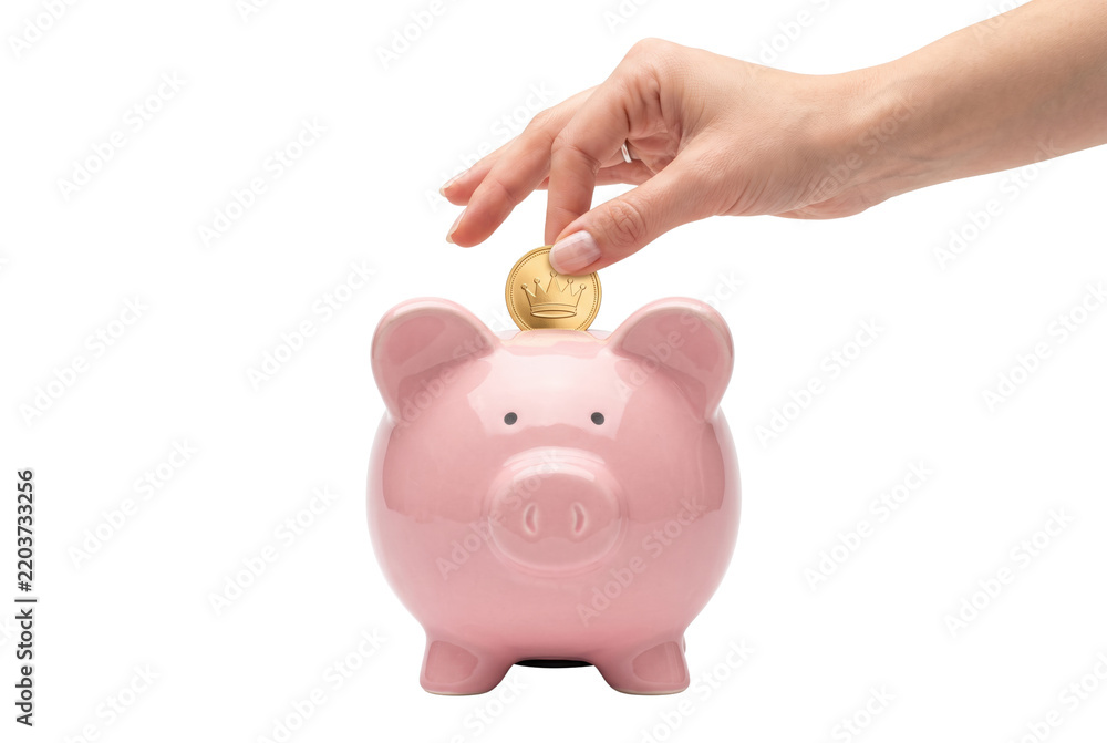 Fototapeta premium Hand inserting gold coin into pink piggy bank