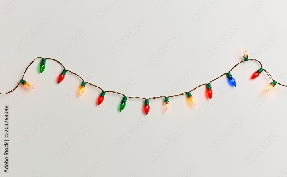 Obraz premium Colorful christmas light bulbs hanging against white background