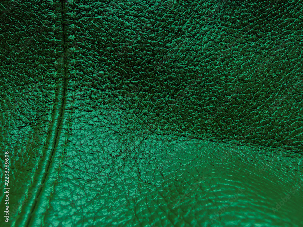 Naklejka premium Texture dark emerald leather pattern, macro. Abstract deep green upholstery surface. Green leather texture with stitching. Dark green leather texture decorated with a seam. Horizontal photo.