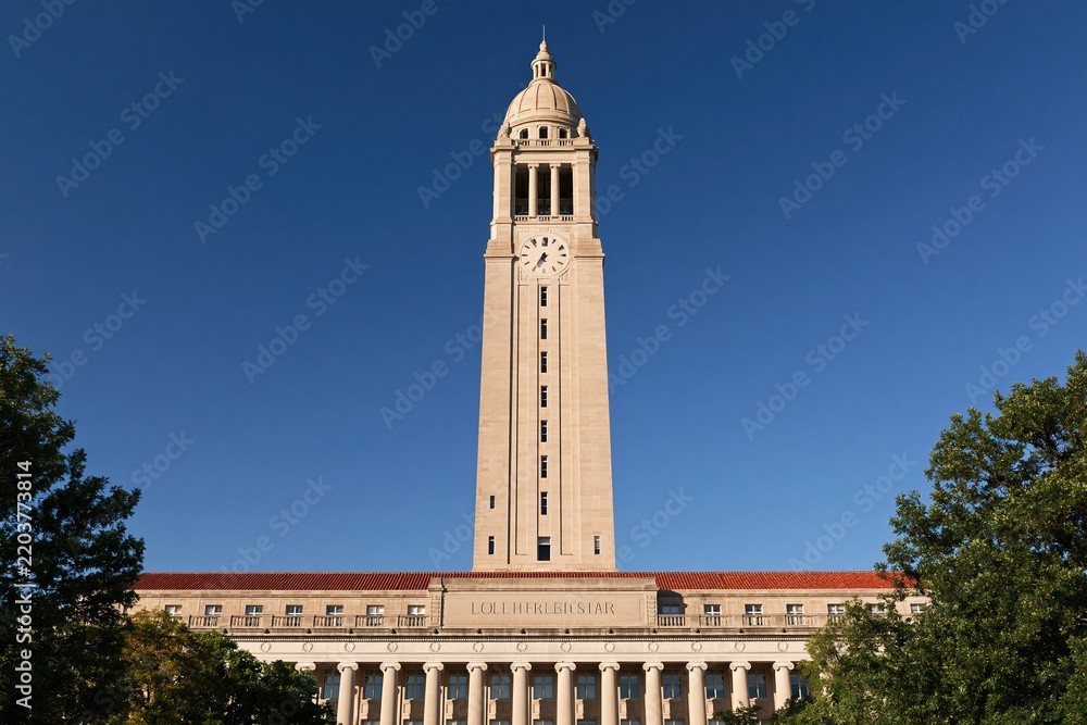 Obraz premium Tall university clock tower against clear blue sky