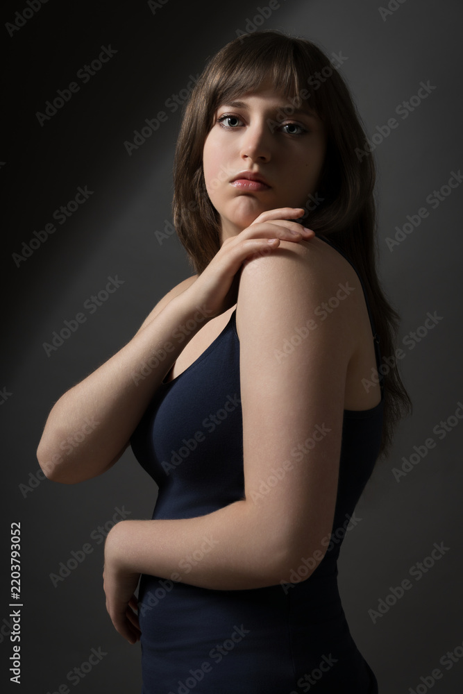 Fototapeta premium Portrait of a beautiful teenage girl posing in dark studio