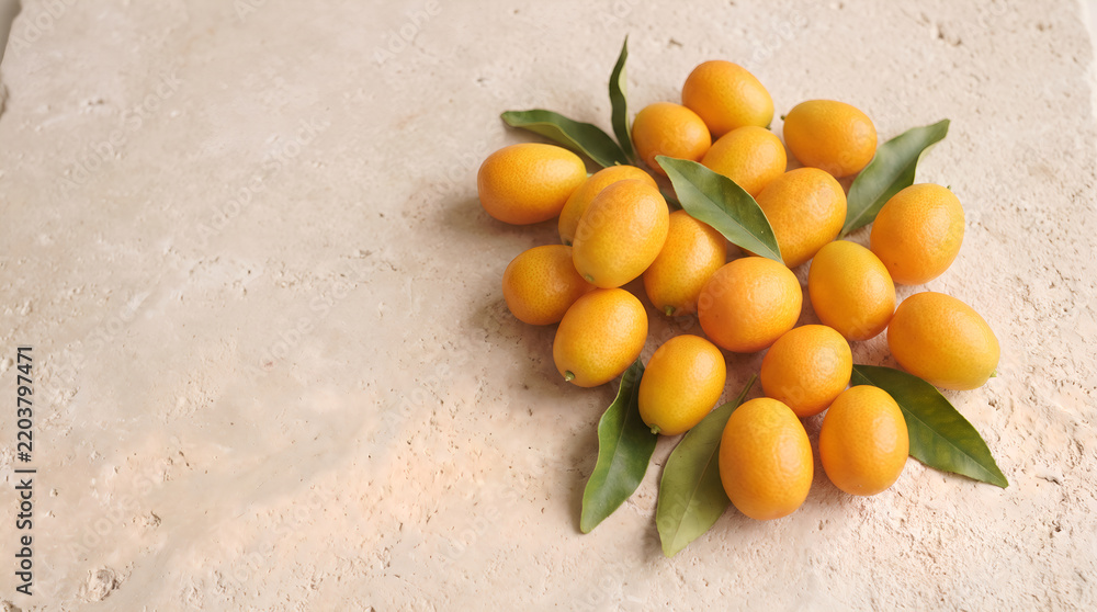 Obraz premium Kumquats with green leaves arranged on limestone surface