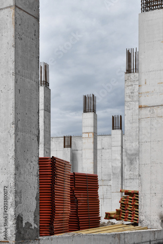 Unfinished concrete building construction site with structural columns and scaffolding