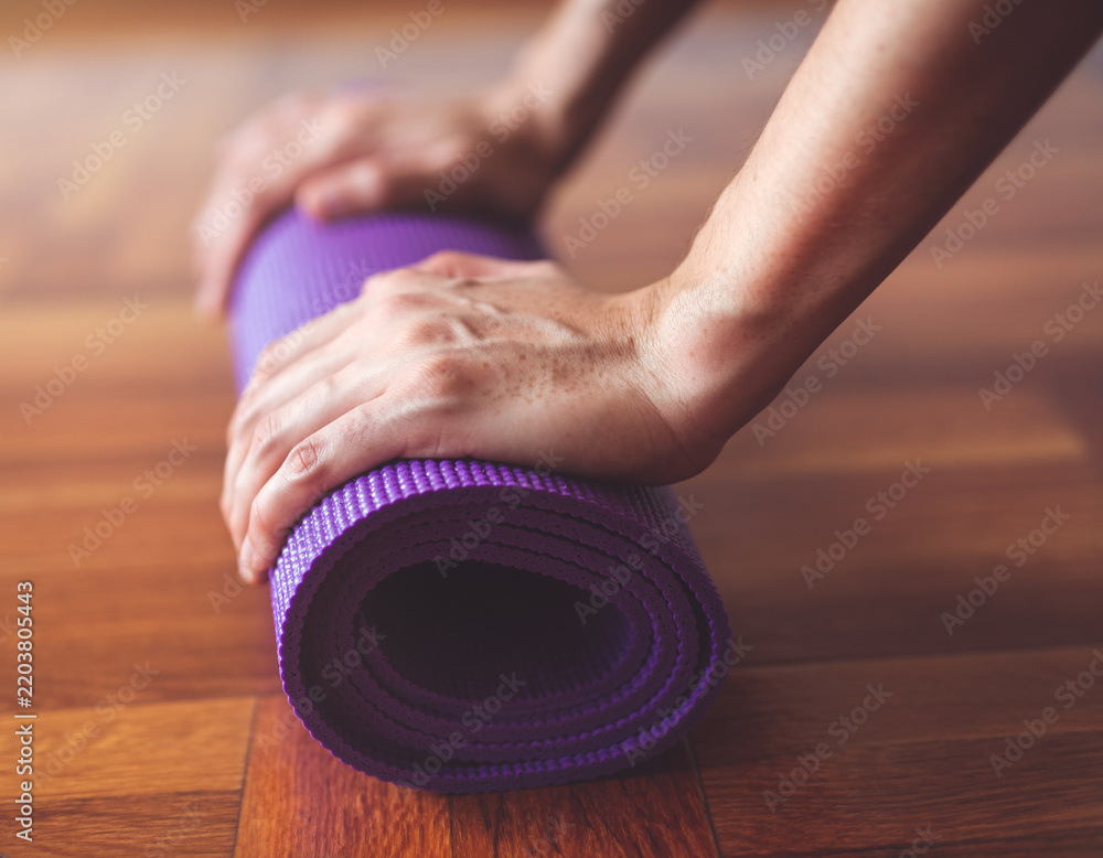 Obraz premium Hands rolling up yoga mat after workout