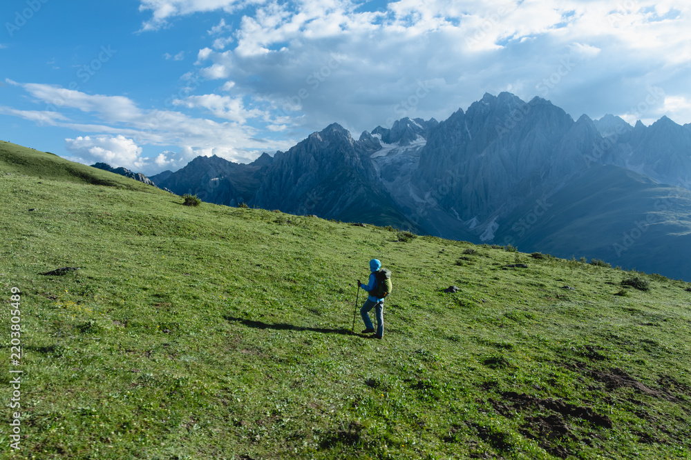 Fototapeta premium Backpacking woman hiking on flowering grassland mountain top