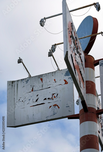 Faded and weathered billboard on a large metal pole