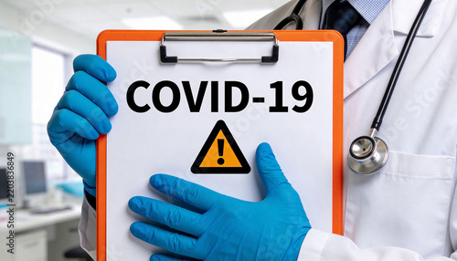 Doctor in white coat holding clipboard with COVID-19 warning sign. Medical worker with stethoscope and blue gloves in hospital. Coronavirus pandemic alert. Health risk and disease outbreak