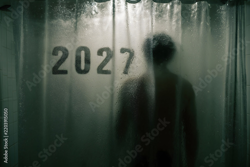 Silhouette of a person behind a foggy glass with 2027 written