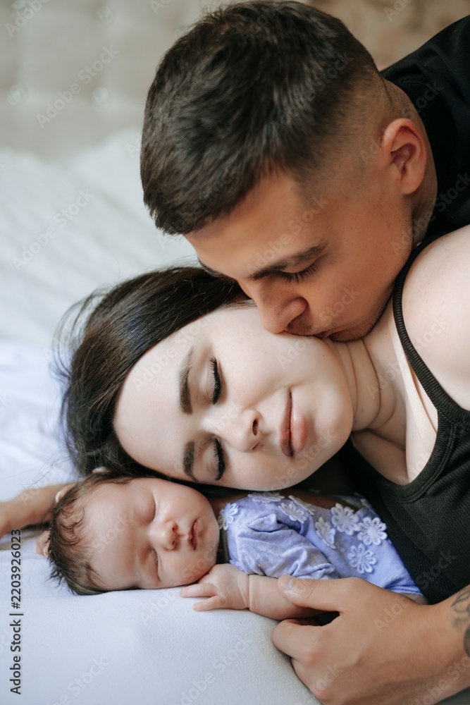 Fototapeta premium A family portrait: mom, dad, and a small child; a happy family with a newborn baby at home.