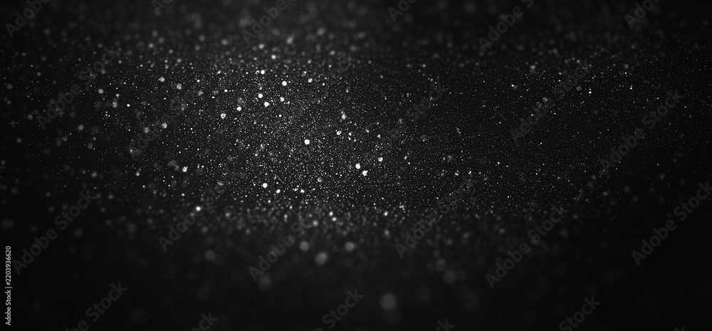 Obraz premium Glowing silver glitter particles. Defocused shimmering dust texture with bokeh effect. Christmas Starry night sky or a magical, festive texture.