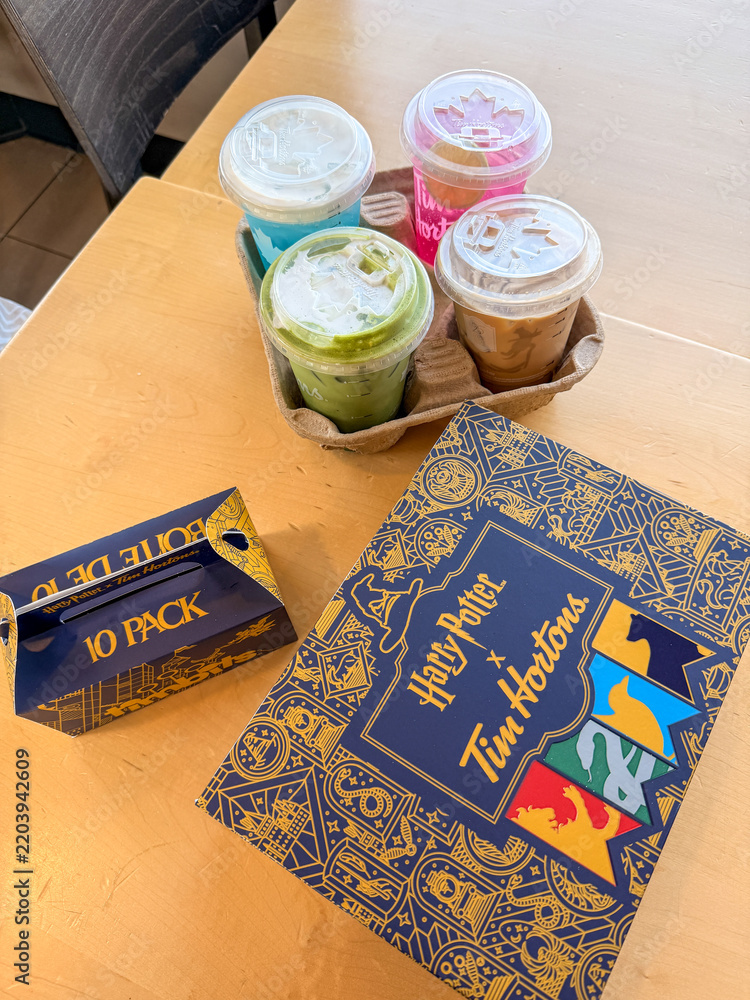 Fototapeta premium Saskachewan, Canada - August 20, 2026: Harry Potter x Tim Hortons limited edition collaboration box and 10-pack timbits with four colorful iced drinks in cardboard carrier on table