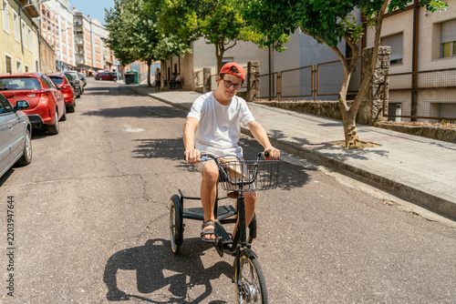 Obraz na płótnie Focused teenage cyclist riding three wheeled bicycle along sunny residential str