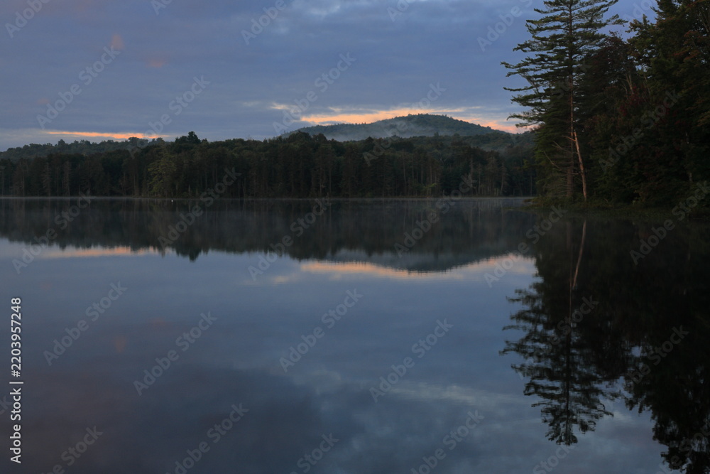 Fototapeta premium Skyline of remote wilderness shoreline reflected in a pond at dusk