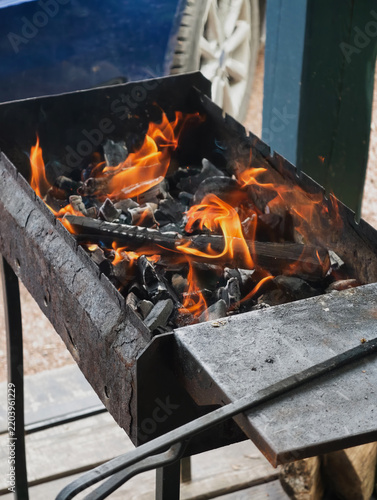 burning wood inside a metal barbecue with a cast iron poker