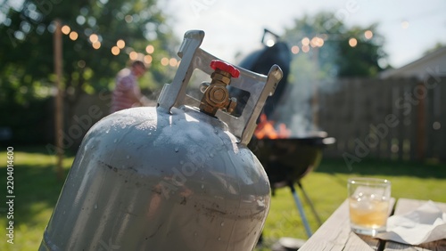 Portable propane tank ready for outdoor barbecue cooking in backyard setting