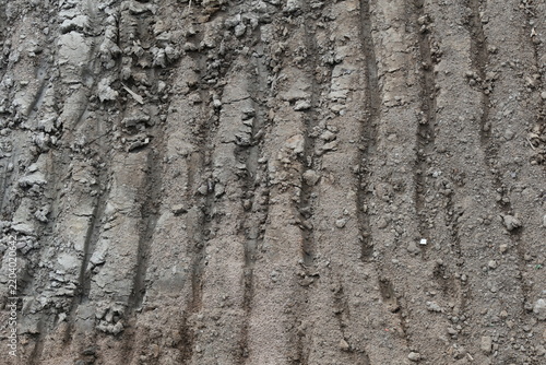 Deep tracks cut through coarse, compacted soil with clumped texture and scattered pebbles
