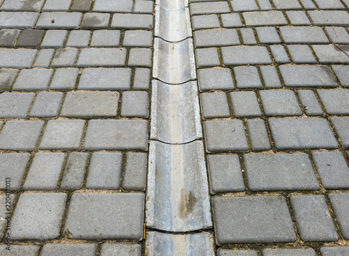 Concrete channel for rainwater drainage among paving slabs