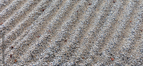 Close-up of light gray gravel arranged in parallel ridges in a traditional Japanese Zen garden, creating a textured abstract pattern associated with calm and meditation