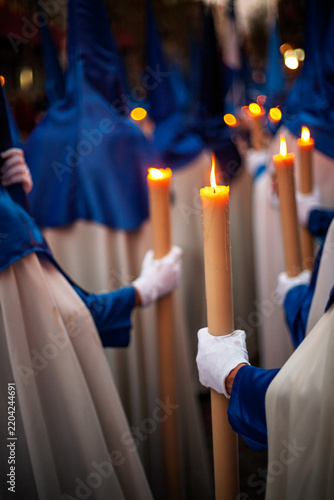 Canvas Print Seville Holy Week: Hiniesta Nazarenos carrying lit candles, selective focus