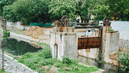 Rustic old manual dam with sluice gates and wheels over a stream heritage water infrastructure