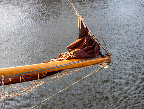 Obraz na plátně Classic Wooden Sailboat Bowsprit with Furled Maroon Sail and Traditional Rope Ri