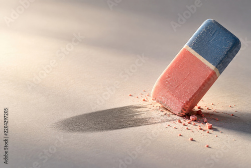 Worn red and blue eraser with scattered crumbs. Space for text.