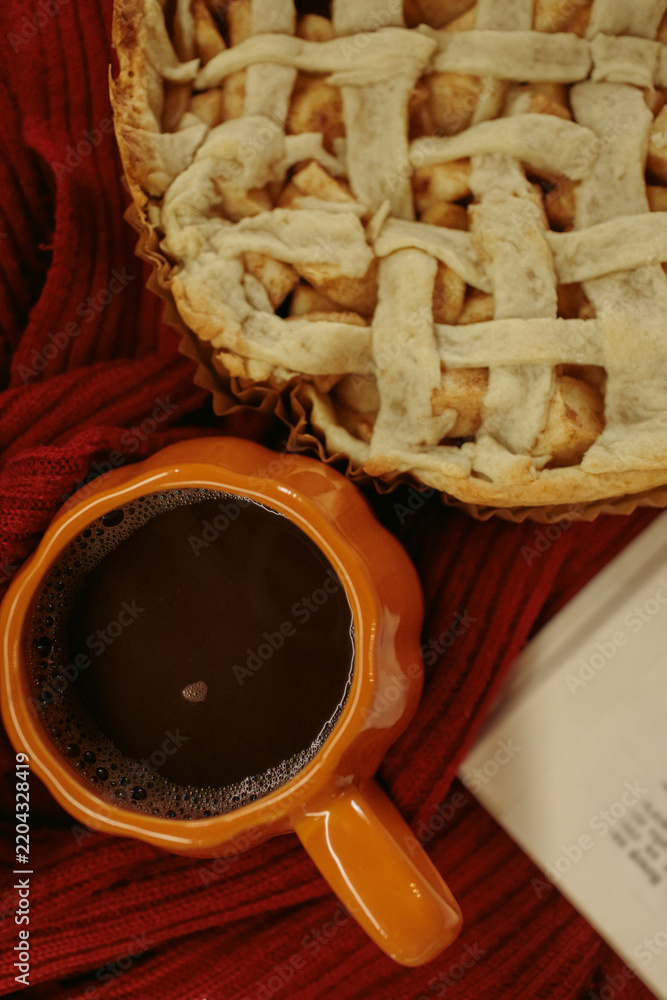 Obraz premium Homemade apple pie with a lattice top next to a cup of hot coffee and an open book, autumn leaf decor, cozy autumn reading setting, film grain effect, high-quality photo