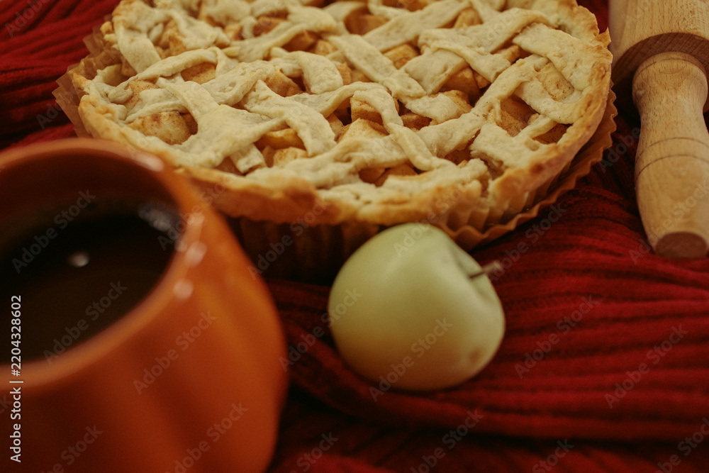 Fototapeta premium Homemade apple pie with a lattice top next to a cup of hot coffee and an open book, autumn leaf decor, cozy autumn reading setting, film grain effect, high-quality photo