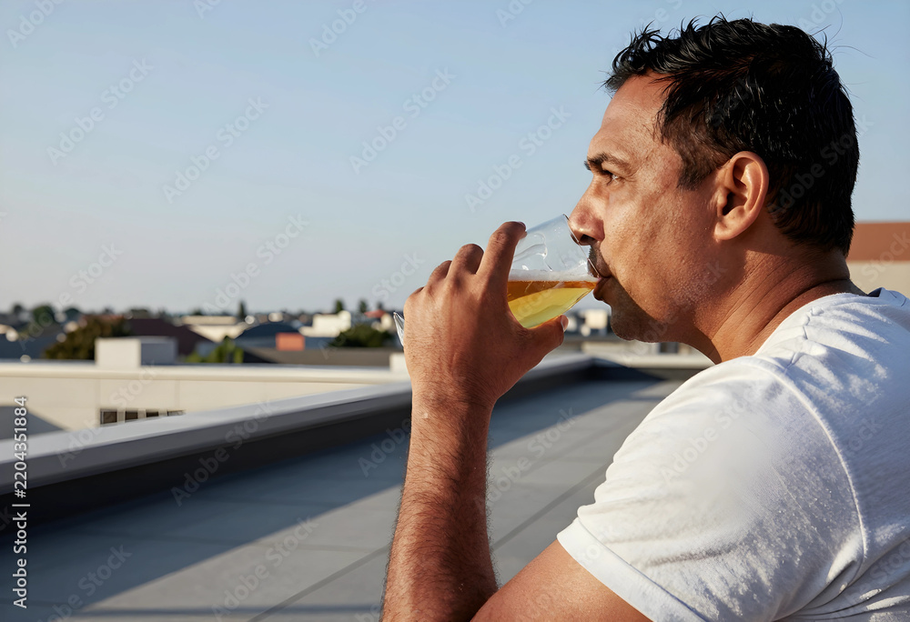 Obraz premium Work-life balance and relaxation, man drinking beer on a rooftop at sunset after work to relieve stress and enjoy leisure time in an urban environment