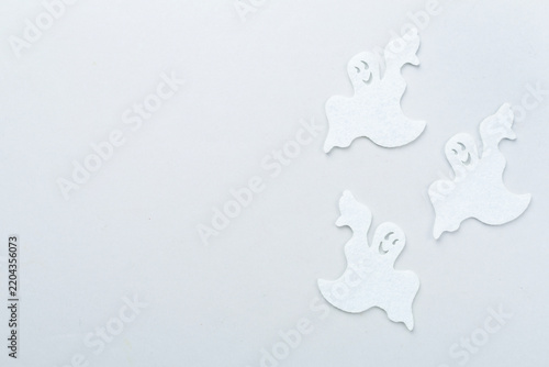 Small decorative halloween ghosts on color background, top view