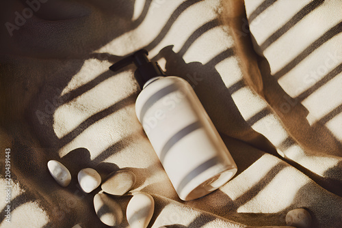 Blank white ceramic pump bottle mockup lying on beige fabric texture with window light shadows