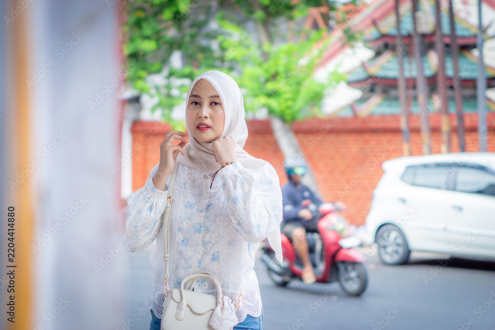 Obraz premium A young Asian Muslim woman wearing a bag and ethnic-style bracelets. Muslim model.