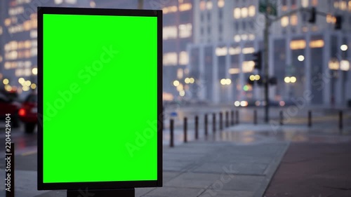 Outdoor advertising mockup: blank green screen board on an urban avenue in soft early morning light, overcast sky. Fast-moving traffic timelapse with cinematic depth of field. Easy chroma key