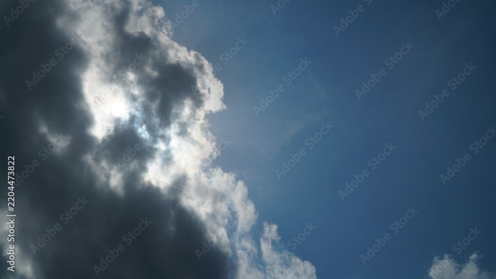 Fototapeta premium Sun Hidden Behind Dark Clouds in Blue Sky with Copy Space