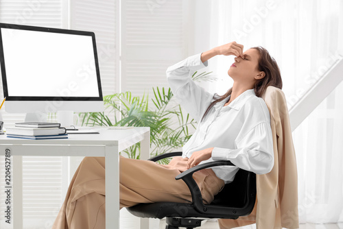 Burnout and workplace stress, exhausted woman sitting at desk with headache a...