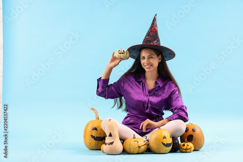 Young woman with Halloween pumpkins on blue background