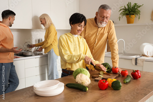 Little boy with his grandfather cutting vegetables in kitchen