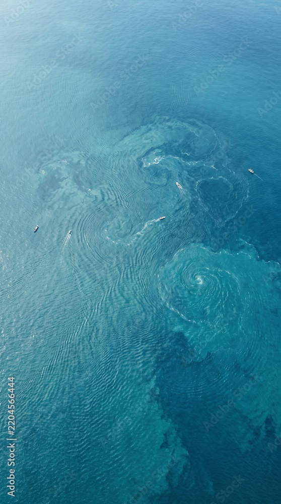 Obraz premium Breathtaking aerial view of turquoise ocean water with natural swirling patterns and ripples, showcasing pristine marine beauty.