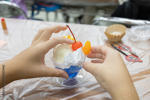 Person making a fake food parfait sample during a hands-on craft workshop